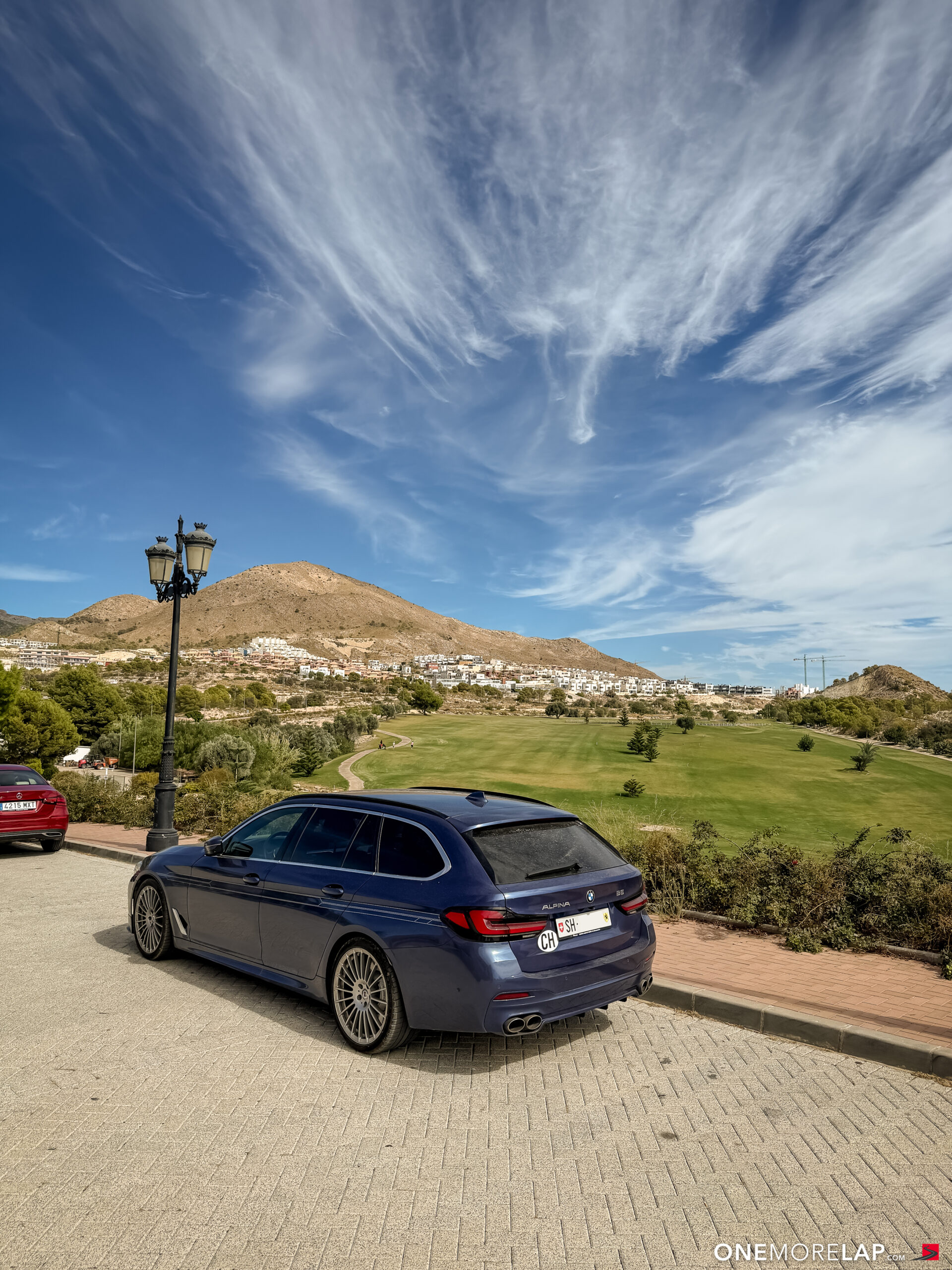 Alpina B5 Touring vor dem Puig Campana Golf unter Federwolken